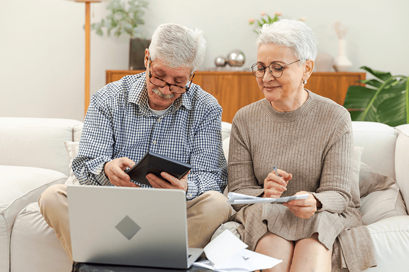 Middle aged senior couple siting with laptop and paper 