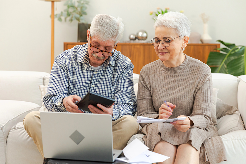 Middle aged senior couple sit with laptop and paper 