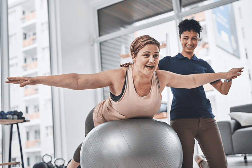 rehabilitation physiotherapist maintaining strength balance stability on exercise ball