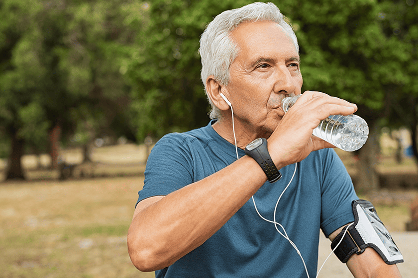 Fit thirsty senior man drinking water before running