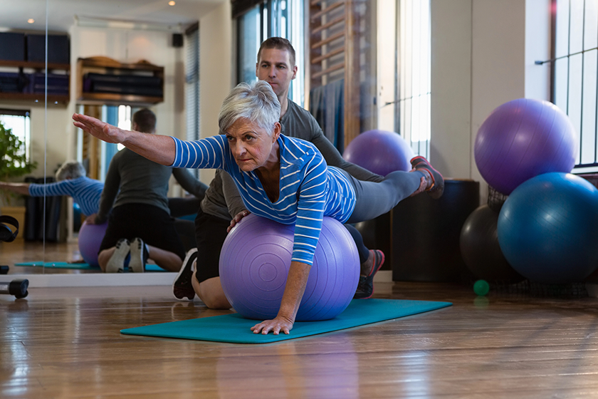 Physiotherapist assisting senior woman in performing exercise