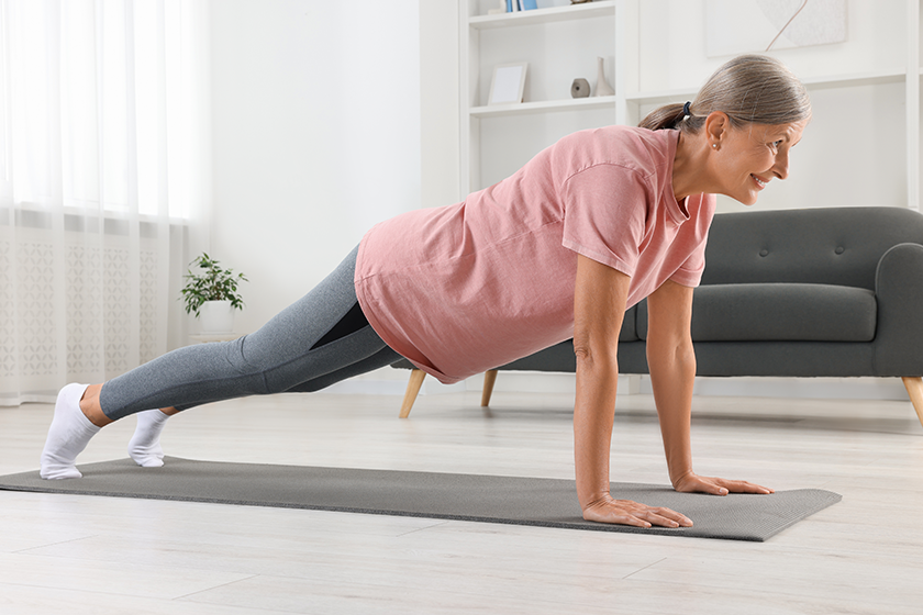 Senior woman in sportswear doing exercises on fitness mat